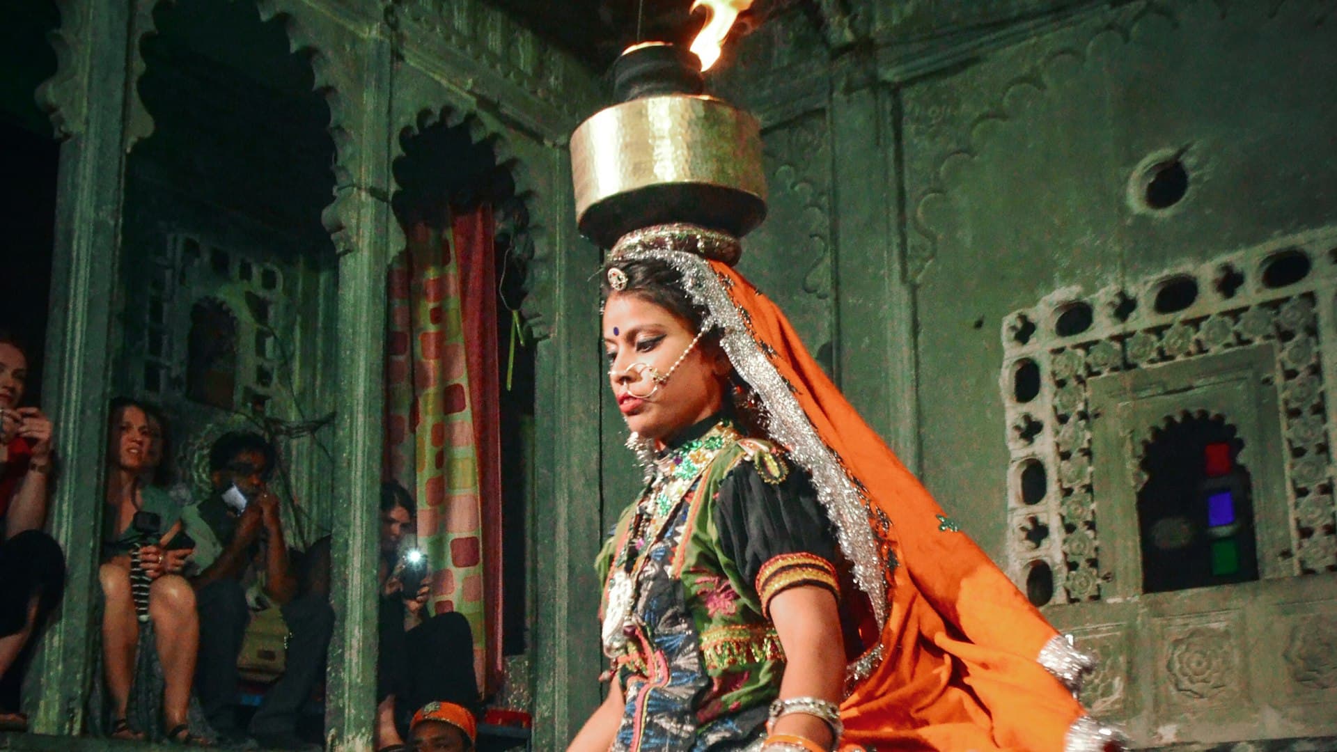Folk dancer balancing a brass pot on her head mid-performance