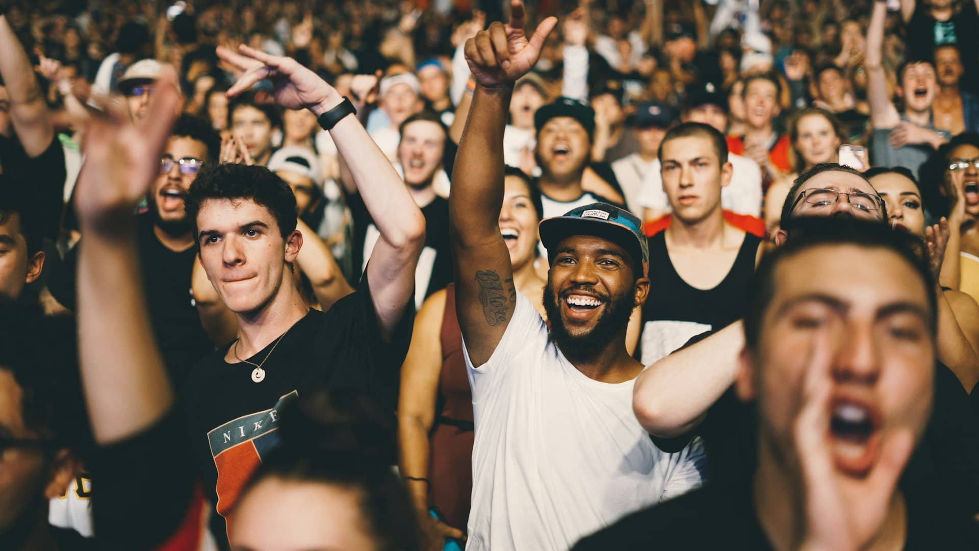 Excited crowd cheering with hands raised at a concert