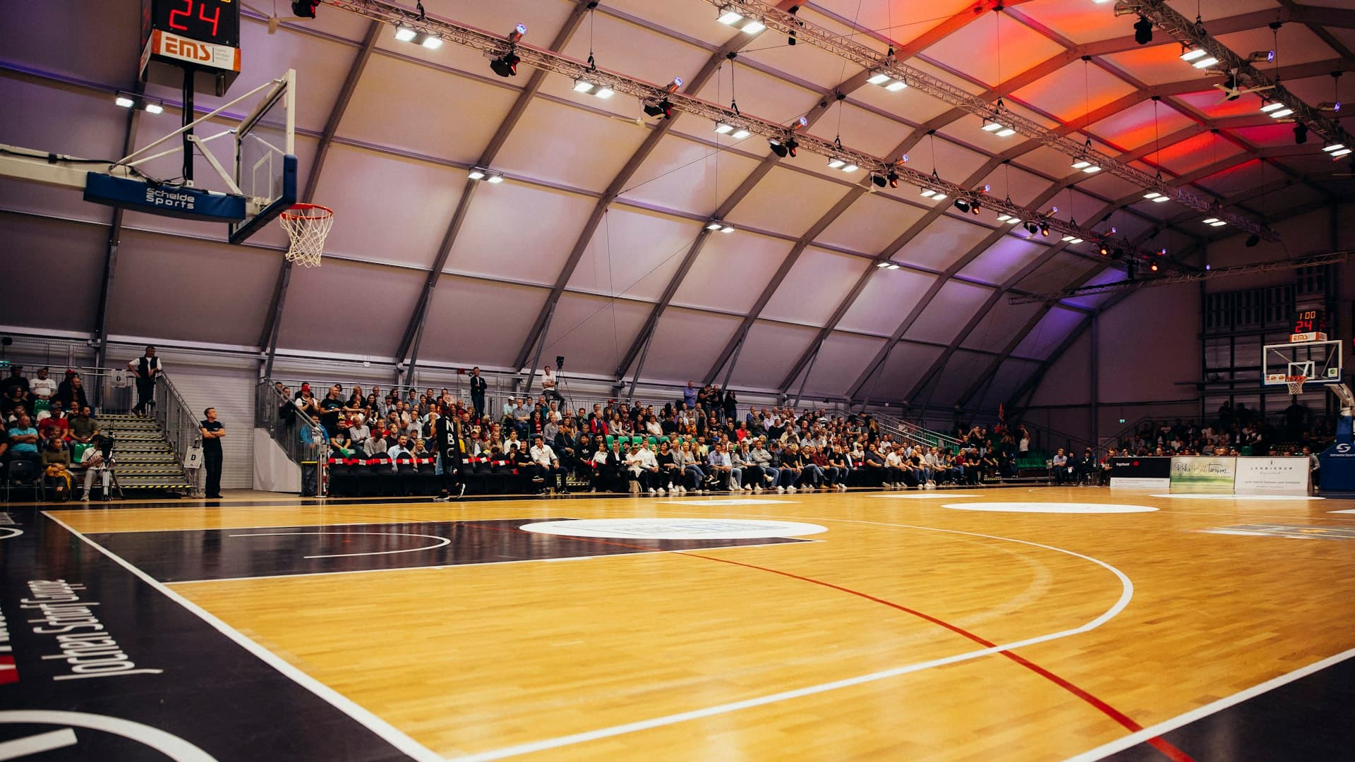 Teams warming up inside a college basketball gym
