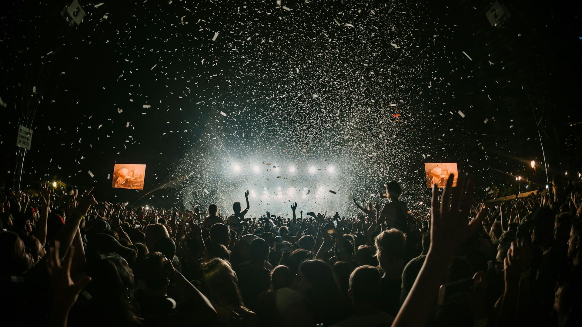 Students gathered on an open field in front of a fest stage at dusk